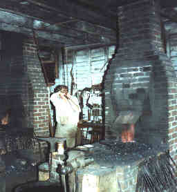 Blacksmith at Colonial Williamsburg pulling the bellows lever rope