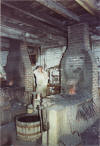 Blacksmith pulling the bellows rope - large side-draft forge at Anderson's Blacksmith Shop - Colonial Williamsburg, Virginia, USA